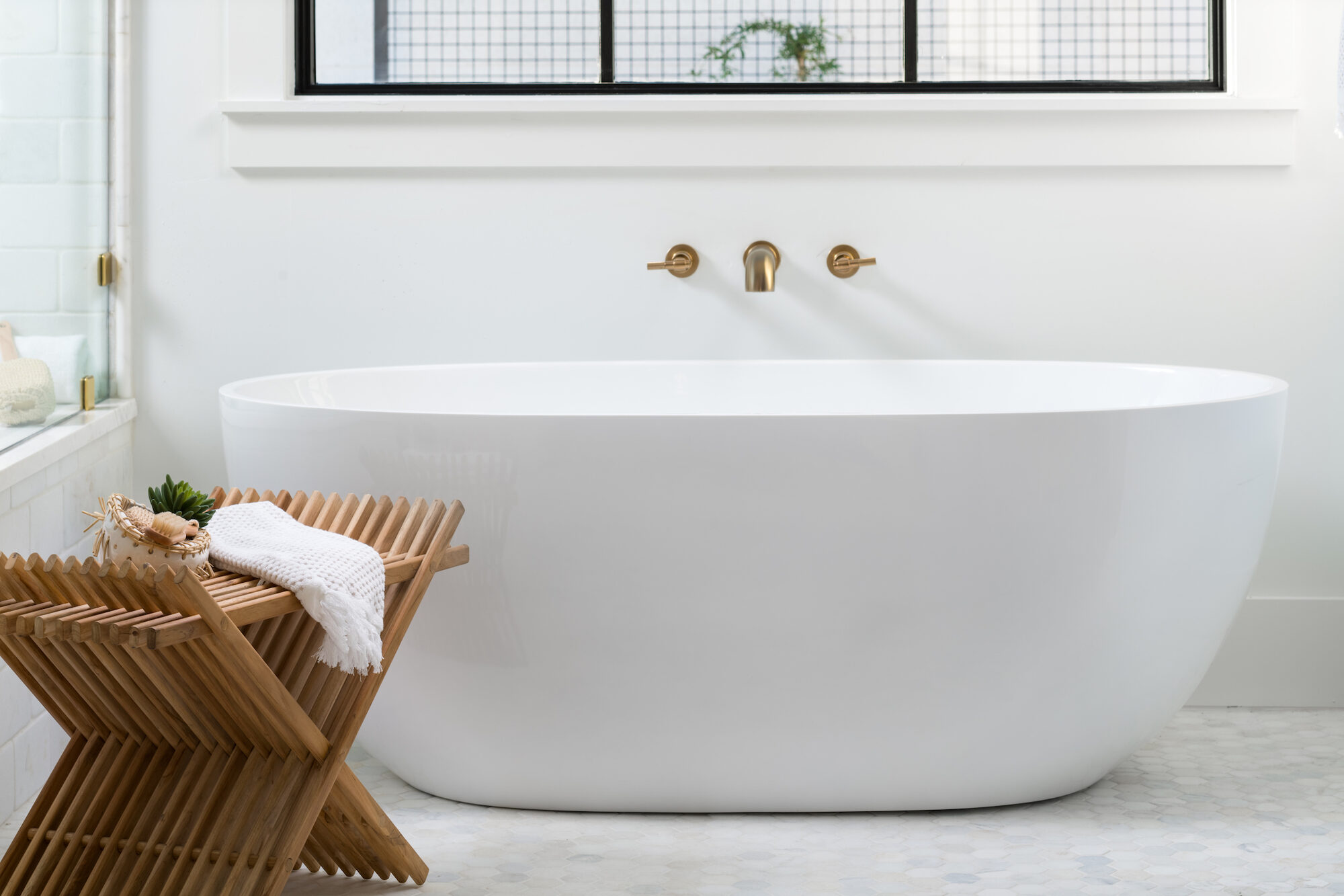 Primary bathroom with marble countertops, gold fixtures, and a vanity with dual sinks