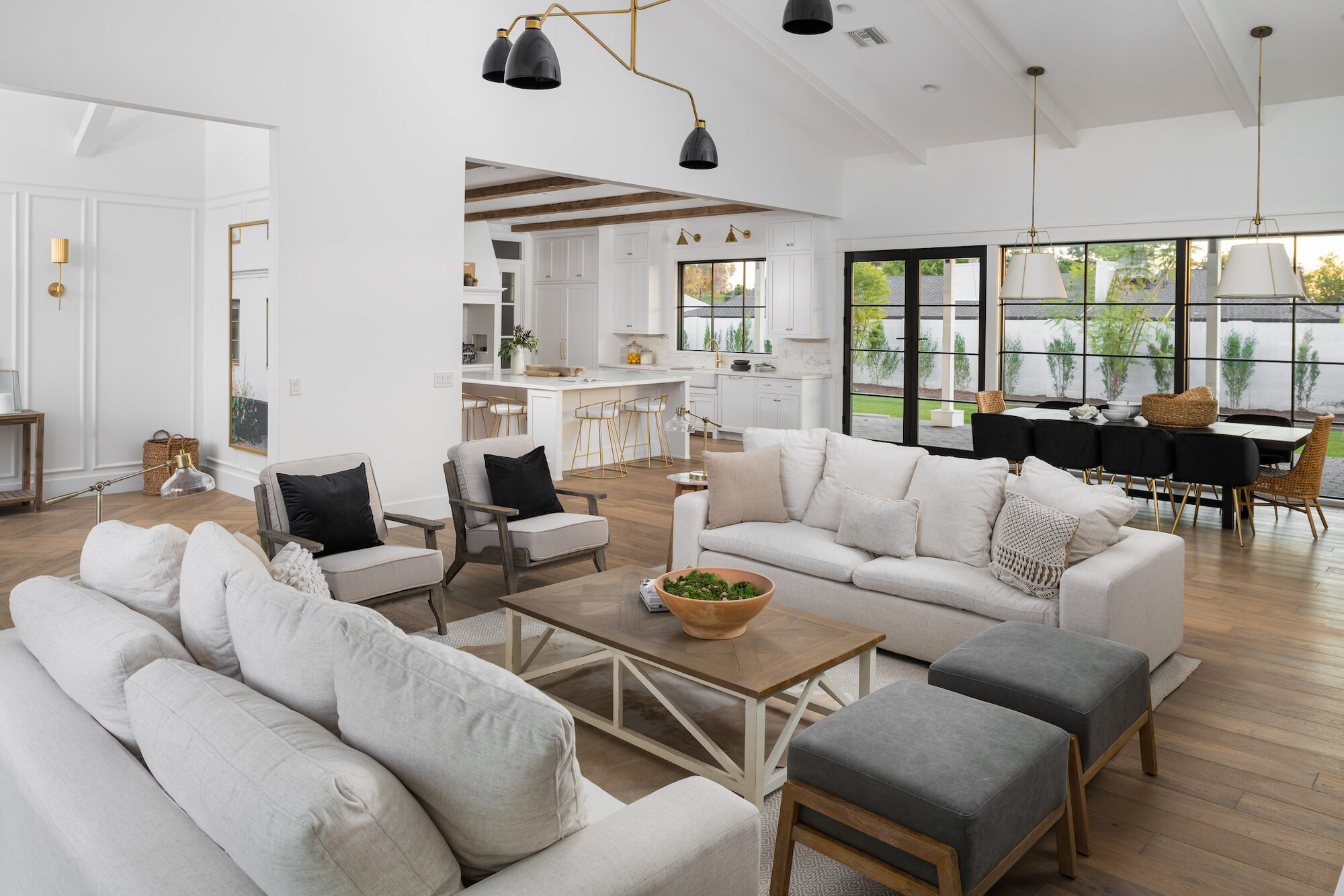 Open great room with vaulted ceilings, wood beams, and floor-to-ceiling windows