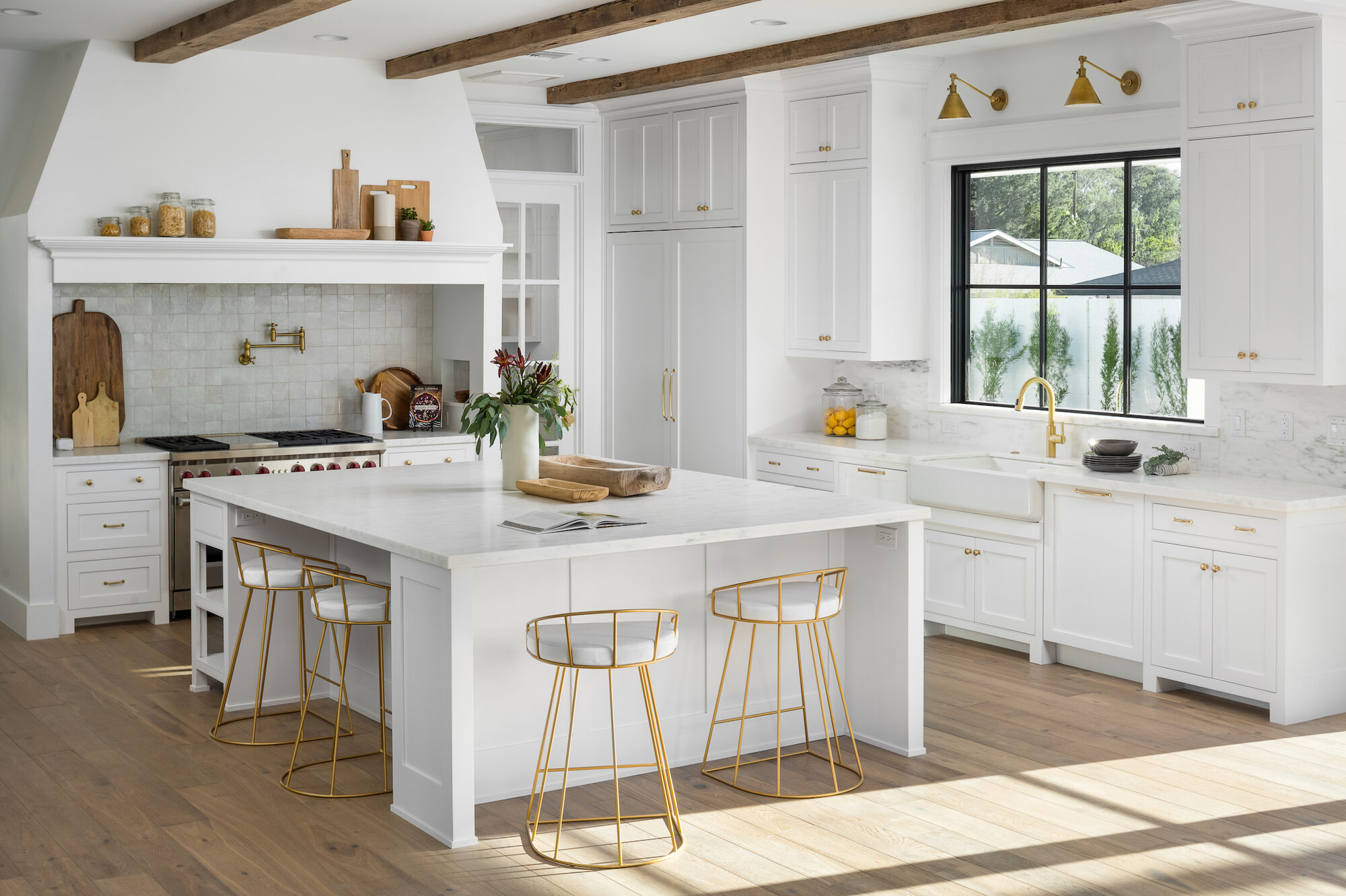 Bright chef's kitchen with white cabinetry, marble countertops, and high-end appliances