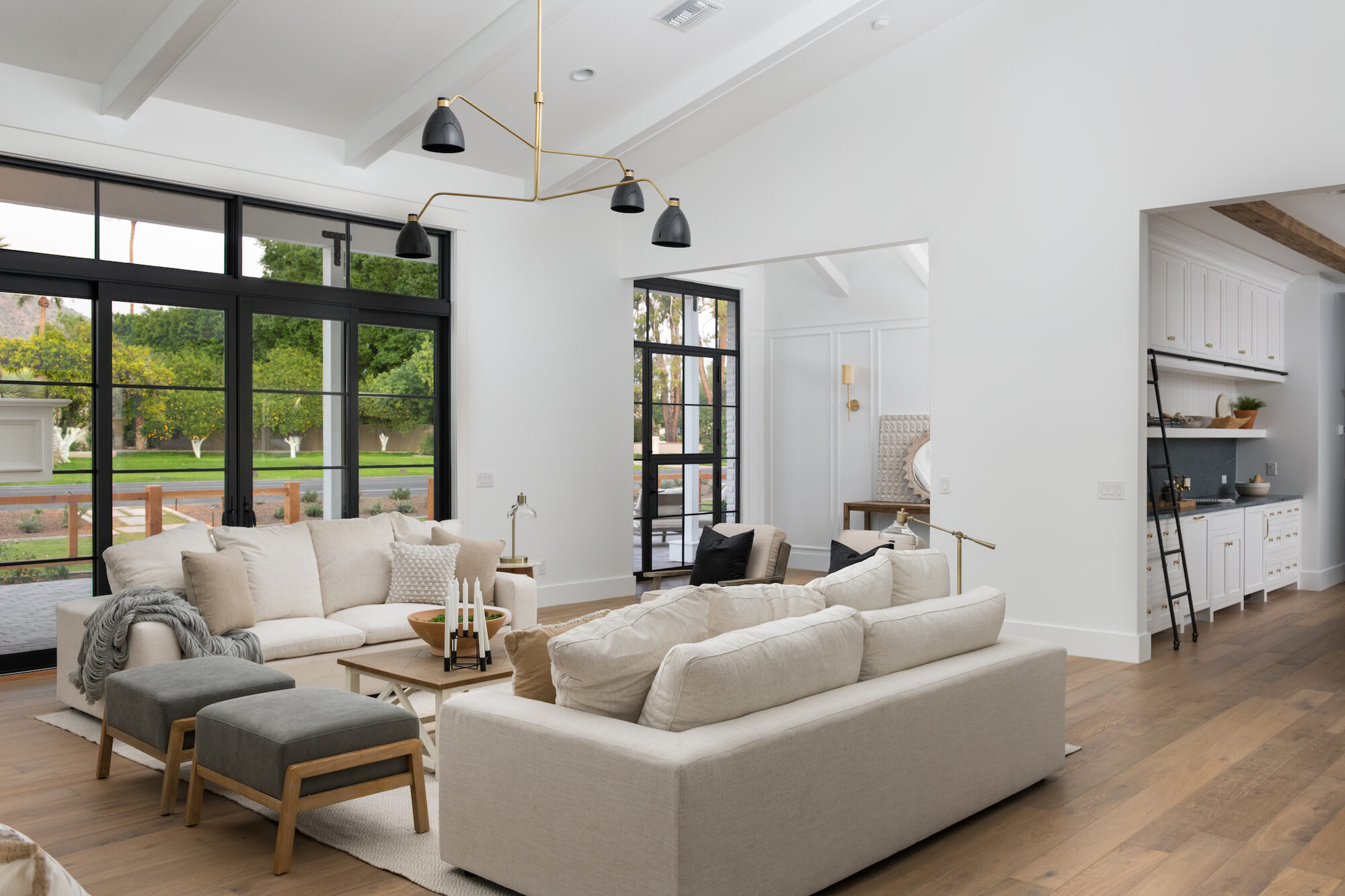 Family room with black steel-framed doors opening to a lush backyard